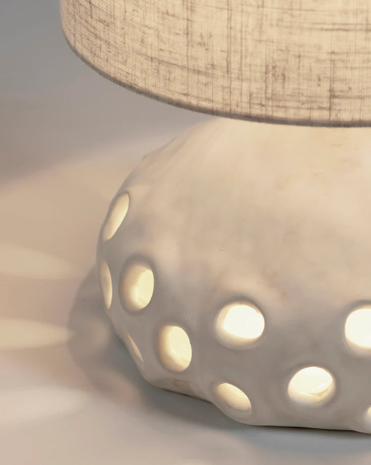 Lampe à poser en grès organique avec abat jour en tissu beige clair et pied de lampe avec des trous
