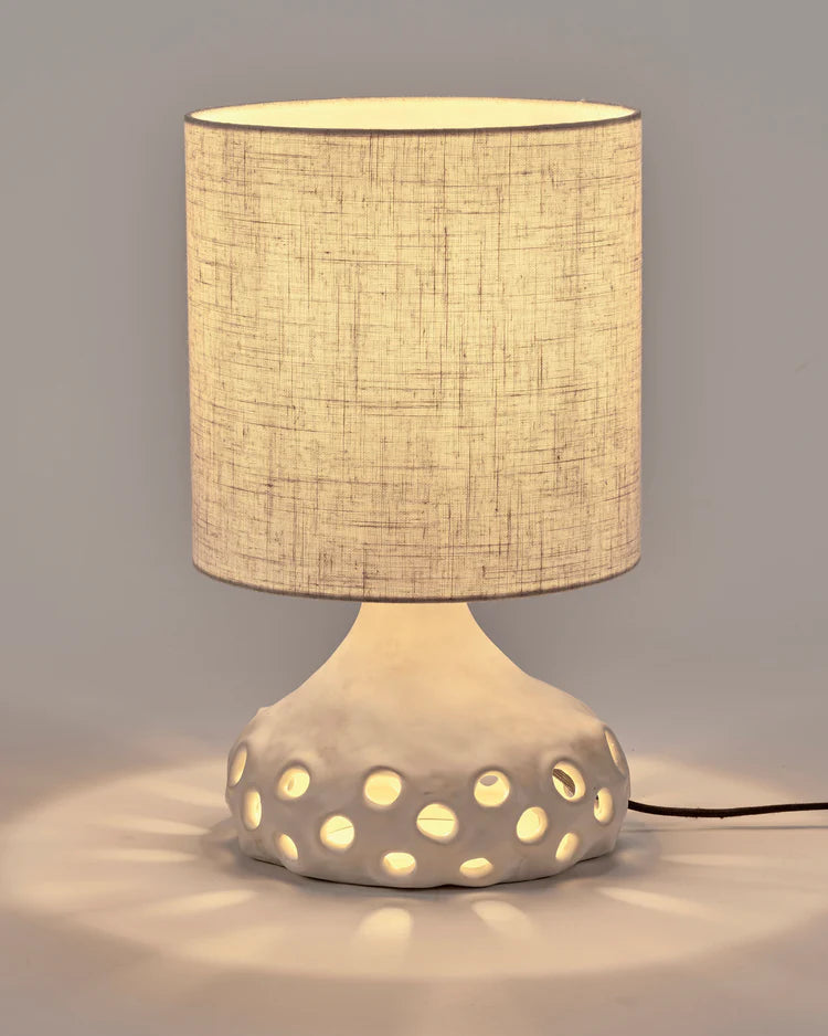 Lampe à poser en grès organique avec abat jour en tissu beige clair et pied de lampe avec des trous